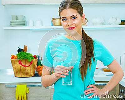 Young woman standing in kitchen with water glass. Stock Photo