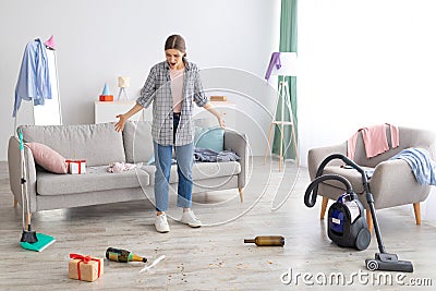 Young woman standing in messy apartment after party, screaming from despair, empty space Stock Photo