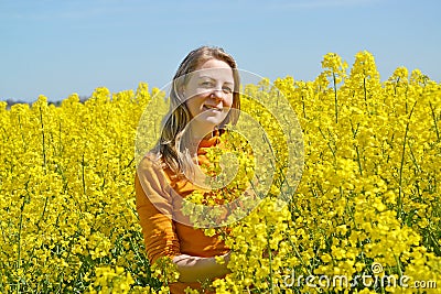 Young woman stands in flowering rapeseed field Stock Photo