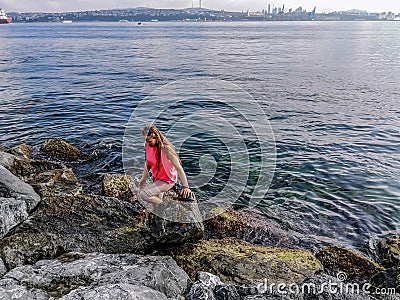 A young woman stands in the water of the Sea of Marmara on the embankment of Istanbul Turkey. Adult European blonde girl on the Stock Photo