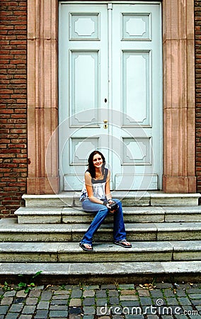 Young woman on steps in front of door Stock Photo