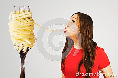 Young woman sucks huge spaghetti from a huge fork Stock Photo