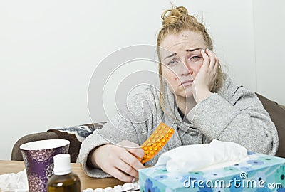 Sick, sadness and tired woman sitting holding a tablet and drugs. Huge headache. Stock Photo