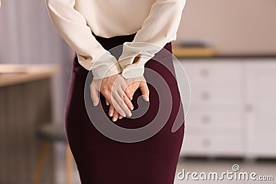 Young woman suffering from hemorrhoid in office Stock Photo