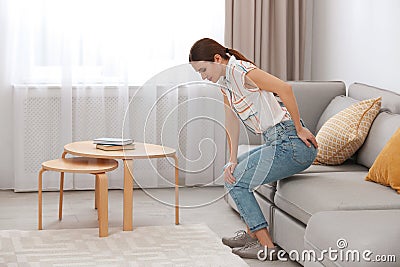 Young woman suffering from hemorrhoid on sofa Stock Photo