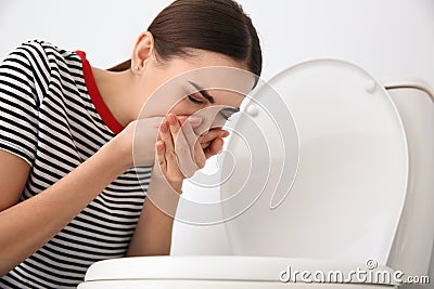 Young woman suffering from nausea at toilet bowl Stock Photo