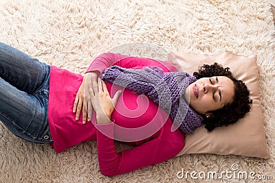 Young woman suffers from cramps on the house floor Stock Photo