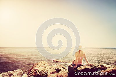 Young woman sunbathing on rocky beach. Vintage Stock Photo