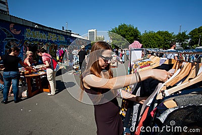 Young woman in sunglasses chooses second hand dress Editorial Stock Photo