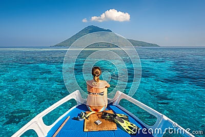 Young woman in swimsuit sit on boat with a mask and flippers loo Stock Photo