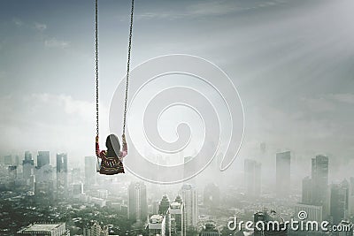 Young woman with swing above misty city Stock Photo