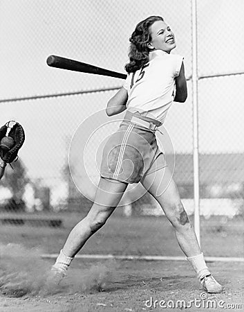 Young woman swinging a baseball bat in a baseball field Editorial Stock Photo