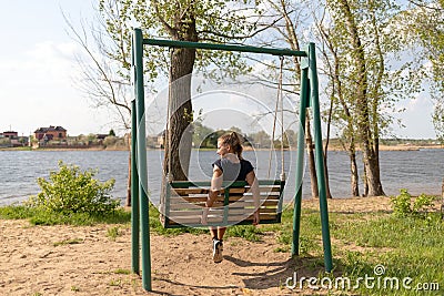 Young woman swinging on a swing. Girl sitting on a swing Stock Photo