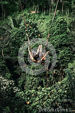 Young woman swings in the jungle of Bali island. Rainforest of Indonesia. Travel concept. Editorial Stock Photo