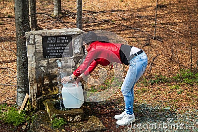 Young woman take a water on drinking fountain in a forest Editorial Stock Photo