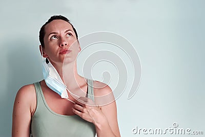 A young woman takes off her medical mask breathing in the air with relief. Copispace Stock Photo