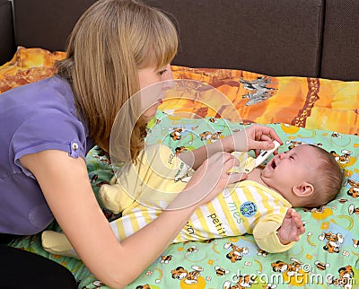 The young woman takes temperature to the sick crying baby the electronic thermometer Stock Photo