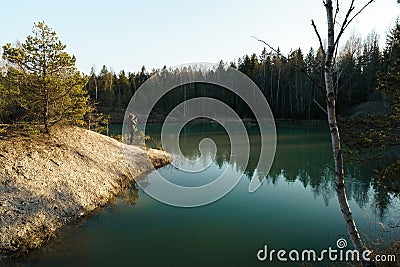 Young woman takes travel photos -Beautiful turquoise lake in Latvia - Meditirenian style colors in Baltic states - Stock Photo