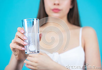 Young woman taking pill against headache. Brunette taking a pill with a glass of water. Woman taking drugs to releave Stock Photo