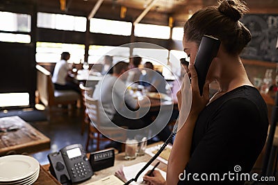 Young woman taking a reservation by phone at a restaurant Stock Photo
