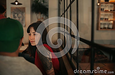 Young woman with tattoos talking with friends in a bar Stock Photo