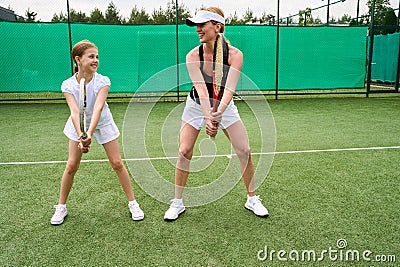 Young woman teaches girl to play tennis Stock Photo