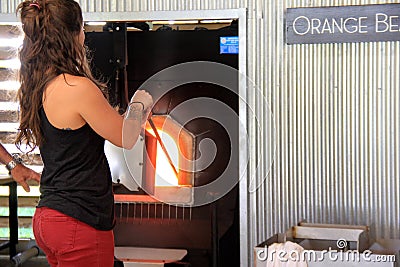 Young woman teaching beach visitors how to create glass blown items, Coastal Art Center, Alabama, 2018 Editorial Stock Photo