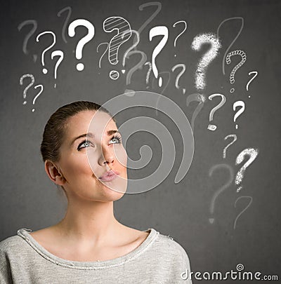 Young woman thinking with question marks over head Stock Photo