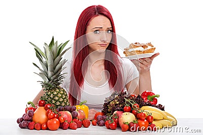 Young woman thinks about eating a cake rather than fruits or vegetables Stock Photo