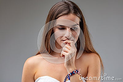 Young woman thinks, two fingers at mouth Stock Photo