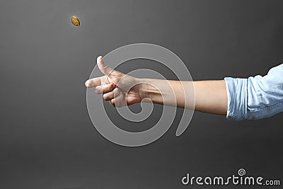 Young woman throwing coin on grey background Stock Photo