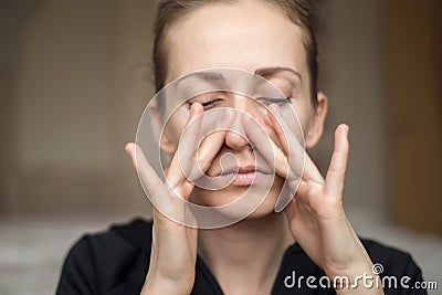 A young woman touches her nose with her fingers because of the loss of her sense of smell, does not feel the smell Stock Photo