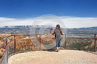 Young woman tourist with american flag admiring of amazing view of Bryce Canyon National Park, Utah, USA Stock Photo