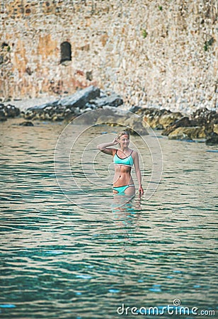 Young woman tourist enjoying sea at beach near fortress wall Stock Photo