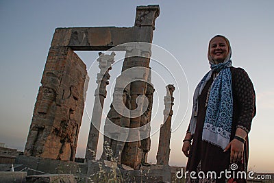 Young woman tourist with a head covered stands on the background of the famous bas-reliefs of the day capital of Persia Iran - P Stock Photo