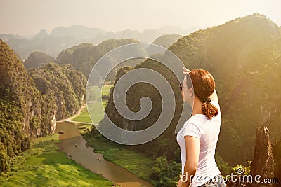 Woman tourist looking far away and enjoying valley and hills view from top of a mountain Stock Photo