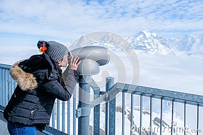 Young Woman Tourist at the Schilthorn using coin operated binocular to enjoy the magnificent panoramic view of the Swiss Skyline Stock Photo