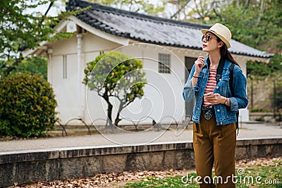 Young woman tourist searching the destination on online map app and finding around. elegant traveler with slr camera looking up to Stock Photo