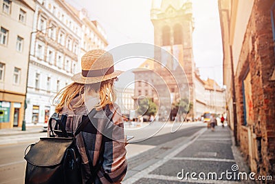 Young woman tourist in straw hat and backpack uses phone as navigator through streets of Europe Editorial Stock Photo