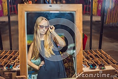 Young woman tourist trying on glasses on Walking street Asian market Stock Photo