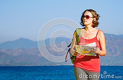 Young woman tourist walks on the seashore reading the map. Stock Photo