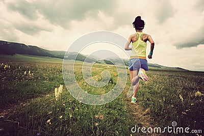 Young woman trail runner running on beautiful prairie trail Stock Photo