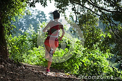 Woman trail runner running on tropical forest trail Stock Photo