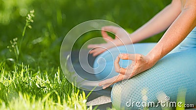 Young woman trainer in blue tracksuit meditates in yoga pose lotus holding hands on knees in leggings Stock Photo