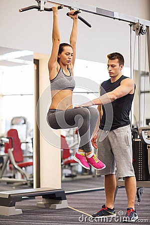 Young woman with trainer doing leg raises in gym Stock Photo