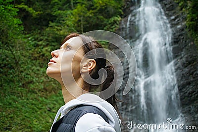 Young woman traveler observes a waterfall Stock Photo