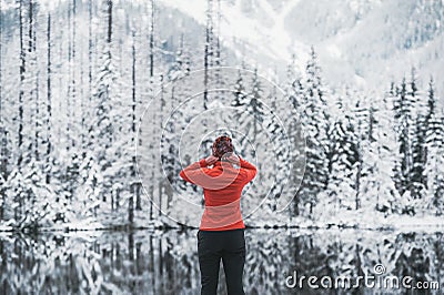 Young woman traveler stay on the snow mountain lake. Back view Stock Photo