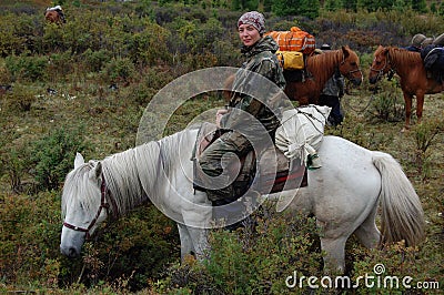 Young woman travels through the moutnains on horseback. Stock Photo