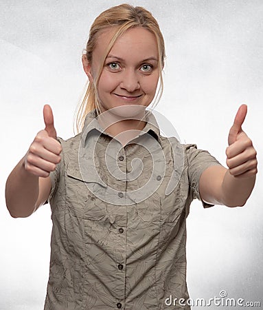 Young woman in trekking shirt with thumbs up looking straight into camera Stock Photo