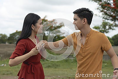A young woman tries to stop her jealous and suspicious boyfriend from taking her phone and reading it. Stock Photo